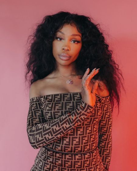 SZA posing for a magazine shoot, off shoulder dress, curly hair with minimal makeup 